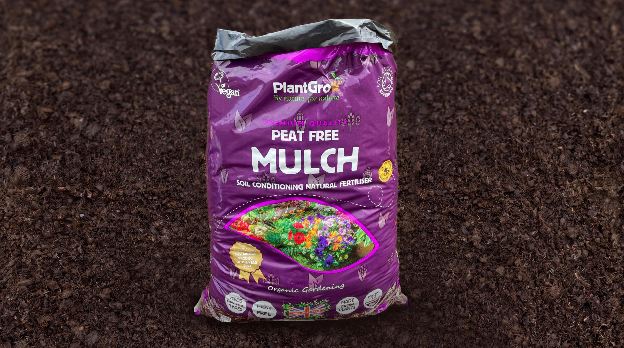 PlantGrow peat-free mulch bag on soil, purple packaging labelled soil conditioning natural fertiliser.