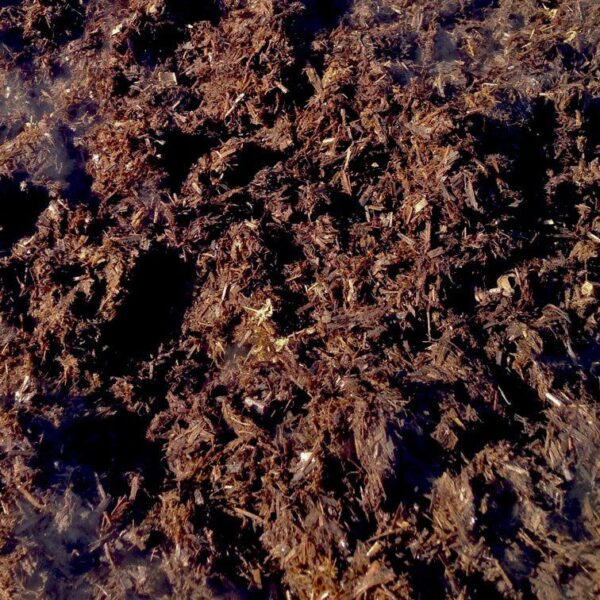 Close-up of natural fertiliser, showing organic plant-based material with dark and golden-brown tones.