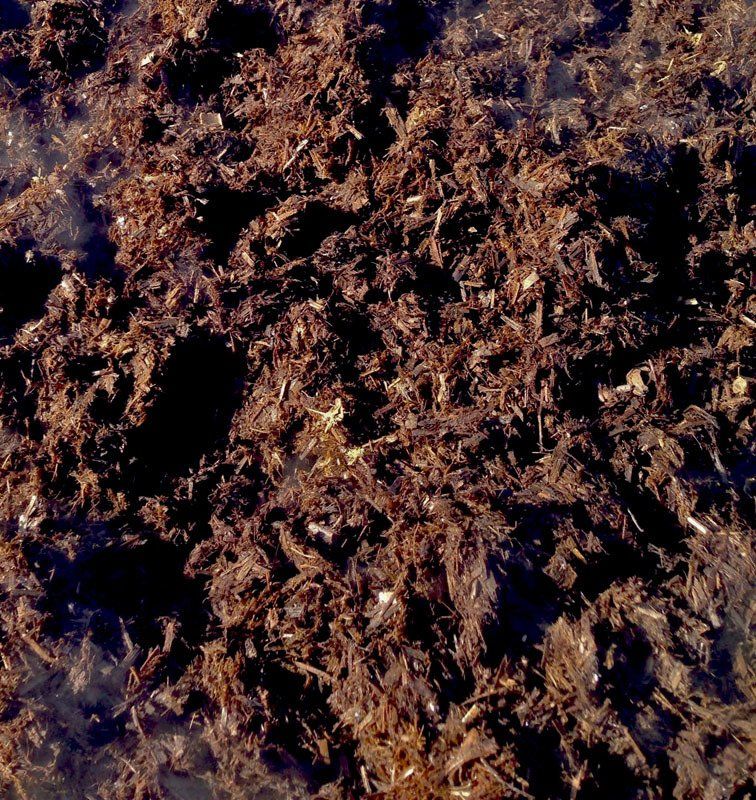 Close-up of natural fertiliser, showing organic plant-based material with dark and golden-brown tones.